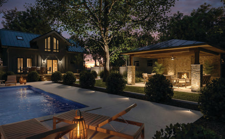 Lit backyard with pool and outdoor seating area. 