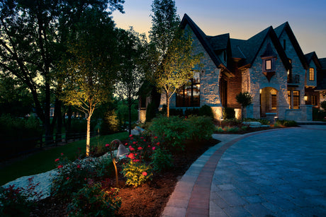 Approach to a stone house lit with landscape lighting